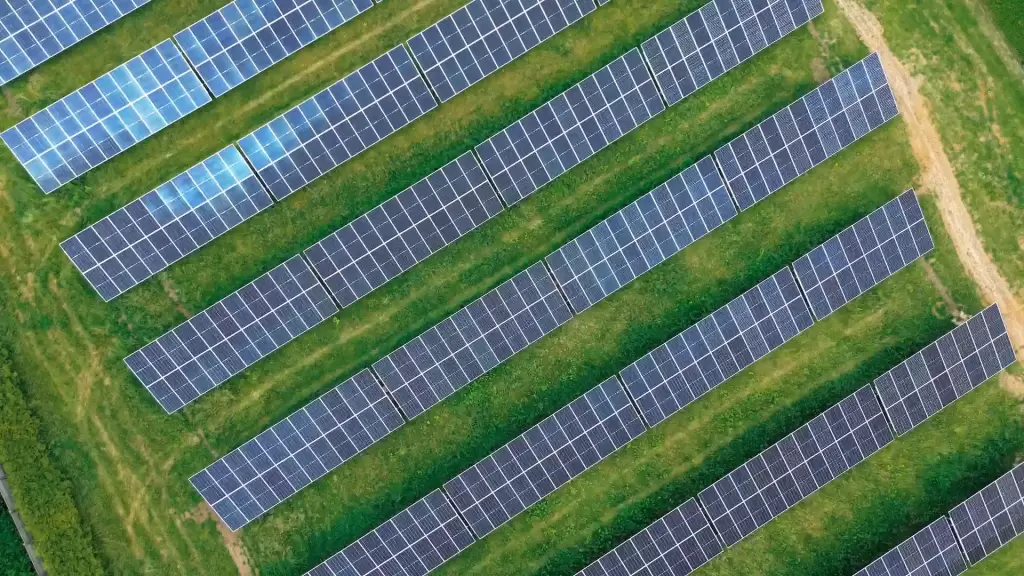 Yeşil tarla üzerinde kuşbakışı açıyla görülen, off-grid ve on-grid güneş enerji sistemleri farkını yansıtan güneş panelleri.