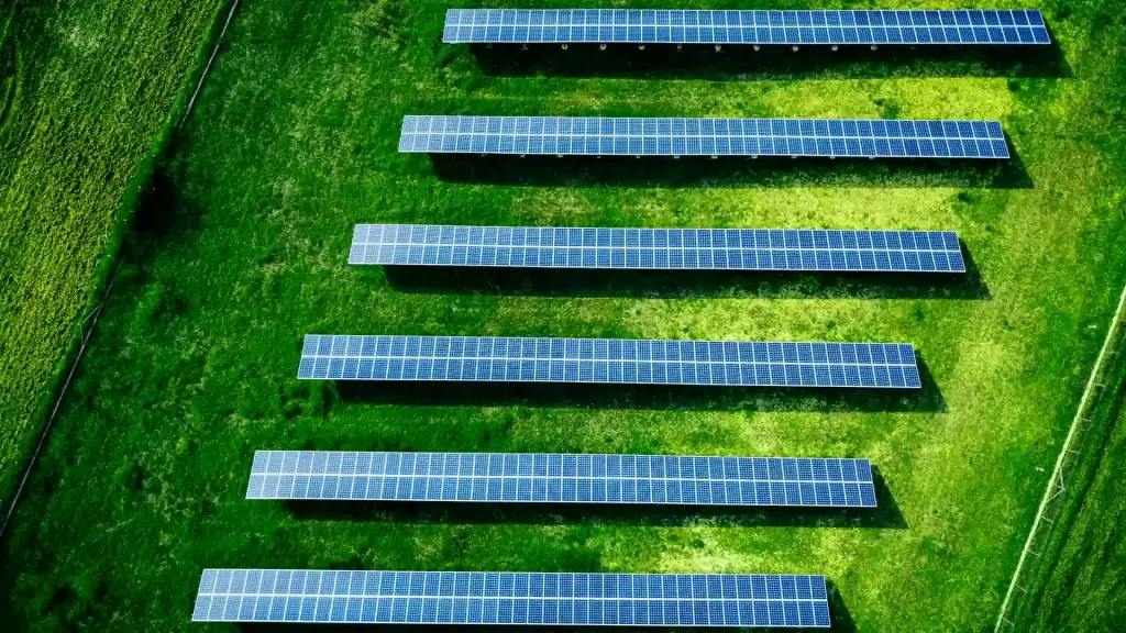 Güneşli bir günde kuşbakışı çekilmiş temiz enerji üreten güneş paneli çiftliği, güneş paneli fiyatlarının akıllı yatırım fırsatını simgeliyor.